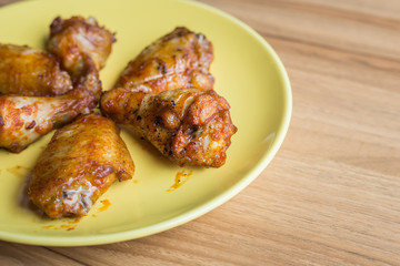 Fried chicken wings in green dish on wooden table