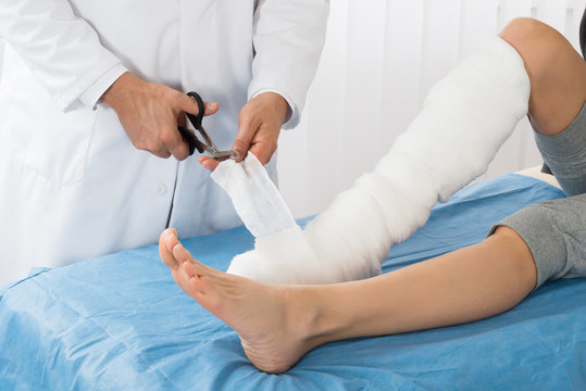 Doctor Bandaging Leg Of Patient