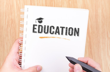 Education word on white ring binder notebook with hand holding p