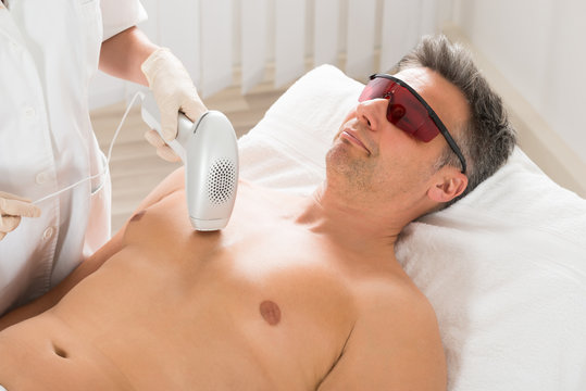 Beautician Giving Laser Epilation Treatment To Man