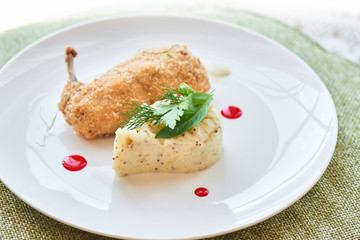 Chicken Kiev fried in breadcrumbs, Parmesan sauce and mashed potatoes with Dijon mustard served on a white plate