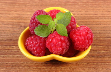 Fresh raspberries and lemon balm on wooden surface, healthy food