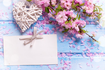 Fresh pink  sakura flowers,  decorative heart and empty tag on b