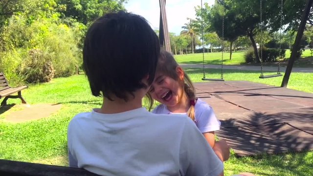 Brother and sister laughing together at the park in a summer sunny day. Brother and sister concept.