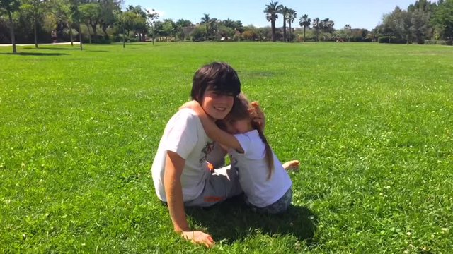 Brother and sister playing together at the park in a summer sunny day. Brother and sister concept.