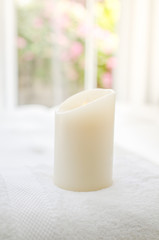 Big candle on towel next to window outdoor, depth of field.