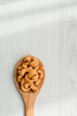 Salty cashew nuts in wood spoon on gray wooden table