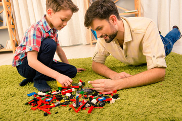 Leisure time. Excited father and son playing with constructor