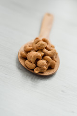 Salty cashew nuts in wood spoon on gray wooden table