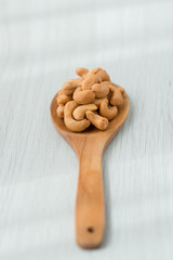 Salty cashew nuts in wood spoon on gray wooden table