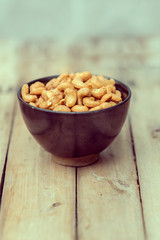salty cashew nuts in black ceramic bowl on wood table