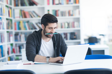 student in school library using laptop for research