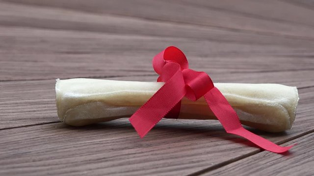 Dog bone with red bow lying on wood
