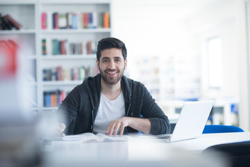 student in school library using laptop for research