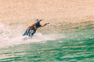 Triathlon training. Young triathlete jumping into the water.