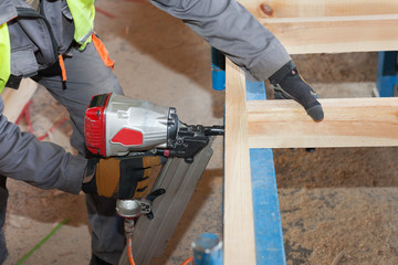 Building a wall for frame house.Worker use Framing Nailer to attach wooden beams