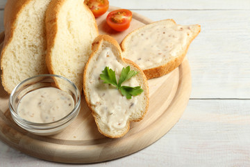 the sauce slathered on a baguette with herbs near tomatoes on wooden cutting Board on wooden background