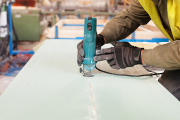 Building a wall for frame house. Worker use Laminate Trimmer for cutting drywall