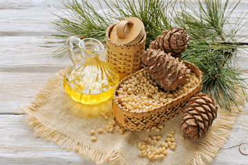 Cedar brunch with cone , peeled nuts , oil on wooden background 