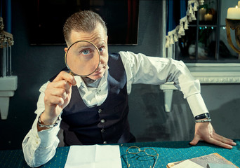 Elegant man with a magnifier in hands