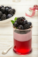 Berry jelly mousse with blackberries and blueberries on white wooden background.