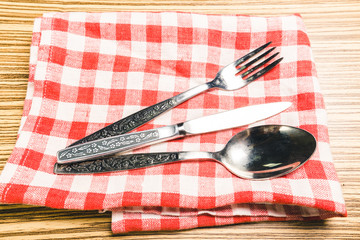 Fork and table knife on red gingham tablecloth