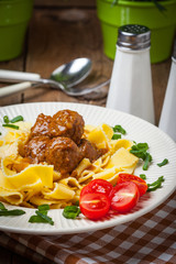 Tagliatelle, meatballs in dark sauce and tomato.