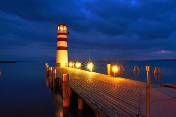 Leuchtturm mit beleuchteten Steg am See zur blauen Stunde