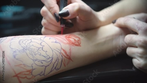 Young Woman Drawing Flower Tattoo Design On Skin Of Arm Of
