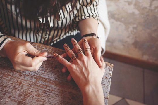 Artist Applying Henna Tattoo On Women Hands. Mehndi Is Tradition