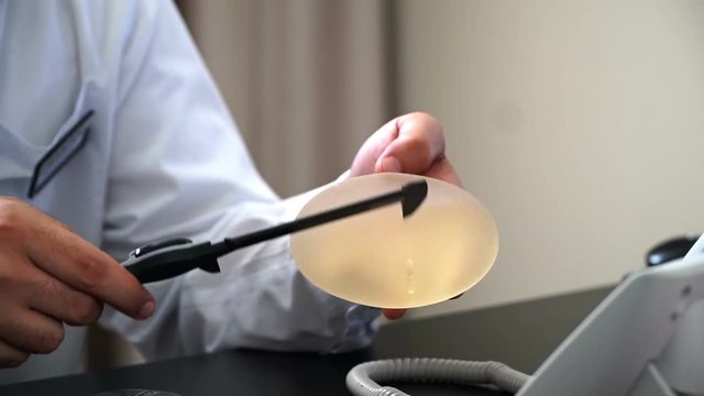 Plastic surgeon demonstrates with breast implant.