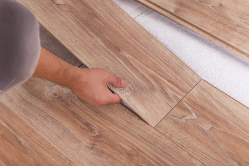 Installing laminate flooring. Carpenter lining parquet boards to