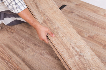 Installing laminate flooring. Carpenter lining parquet boards to