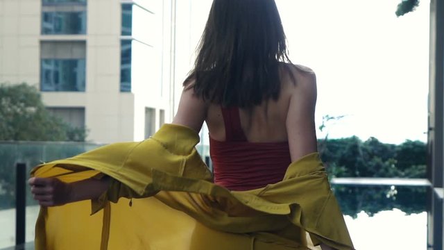 Sexy woman taking off her dress standing close to the swimming pool, super slow motion 
