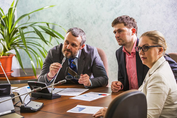 At the meeting colleagues talk on the speakerphone in the conference room at the meeting