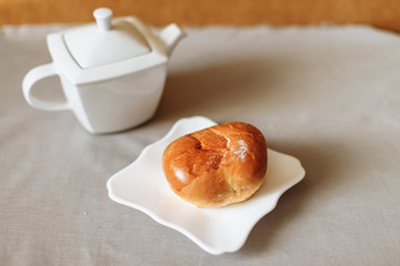 bun and tea breakfast on a gray fabric background white dishes