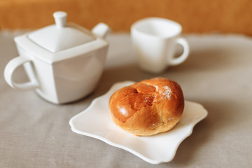 bun and tea breakfast on a gray fabric background white dishes