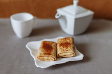 pancakes stuffed with tea and breakfast on a gray fabric background white dishes