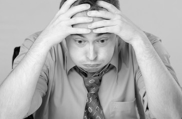Worried tired stressed out businessman holding his head.