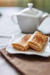 pancakes stuffed with tea and breakfast on a gray fabric background white dishes