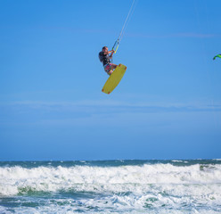 Athletic man riding on kite surf board at sea waves