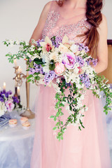 fashion studio photo of gorgeous young woman with dark hair in elegant dress posing with spring flowers 