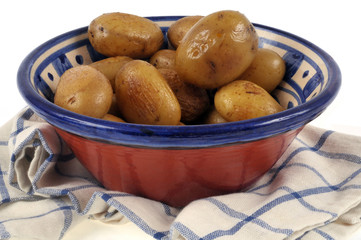 Pommes de terre cuites avec la peau dans un saladier posé sur un torchon