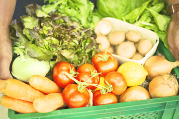 Man holding crate with fresh organic vegetables