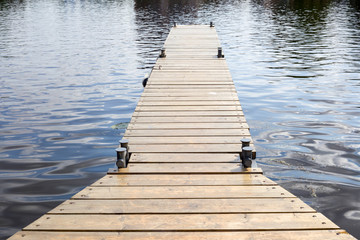 Fototapeta premium Long old wooden pier in water at summer time