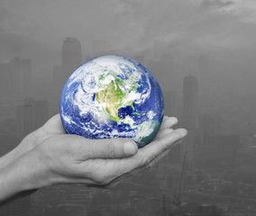 Earth in black and white hands over pollution city, Environment