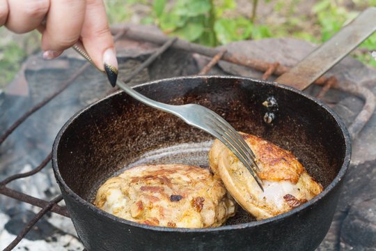 Cooking outdoors . Fried chicken meat . prepare on fire . On a frying pan . to fry meat . Tasty and appetizing
