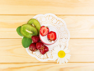 Bowl  pureed fresh strawberries, kiwi slices in background light wood.