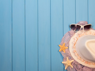 Beach accessories: hat, sunglasses on  background of blue painted wood.