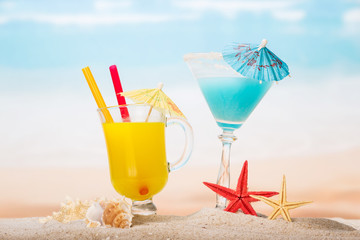 Cocktail, orange juice, starfish and shells on  beach.